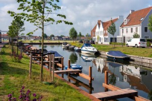 Water with boats and Dutch houses at the waterfront. 