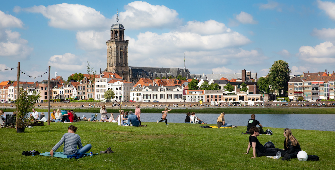 city view with church and in the front people on the grass 